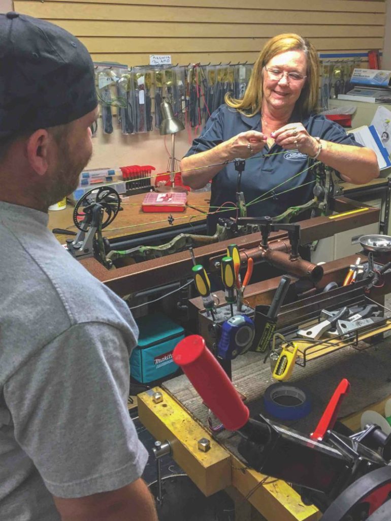 Woman working on bow in archery shop 770x1025