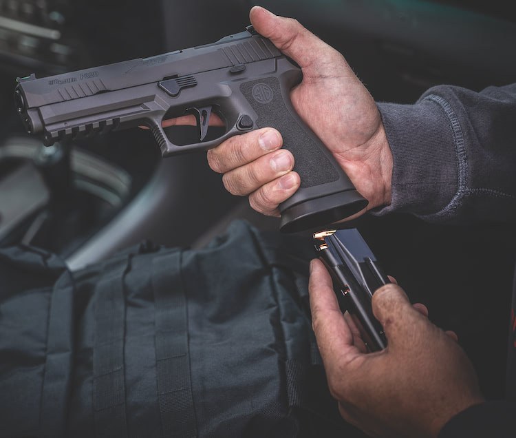 SIG Sauer hand gun with hand loading the magazine background interior of vehicle
