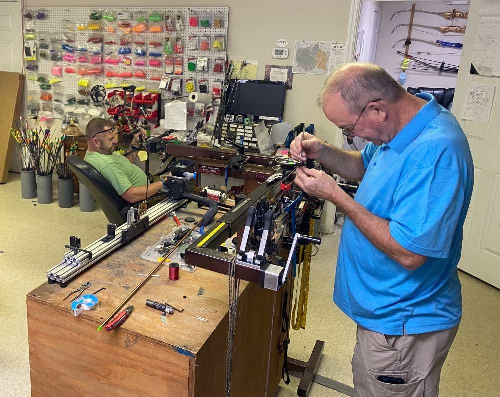 Cropped Steve Williams with Custom Archery Center works on a bow in the press