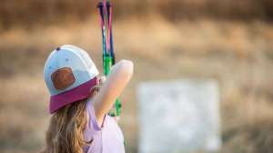 Girl shooting bow in backyard