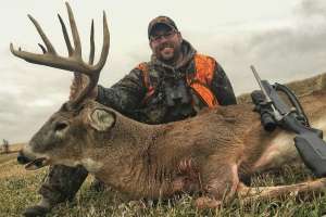 Deer hunter with big buck and rifle