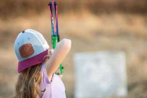 Girl shooting bow in backyard